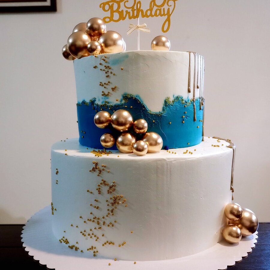 Pastel real de dos pisos con goteo turquesa y esferas doradas